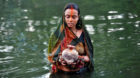 A Hindu devotee holds offerings as she worships the Sun God in the waters of a pond during the religious festival of Chhat Pu