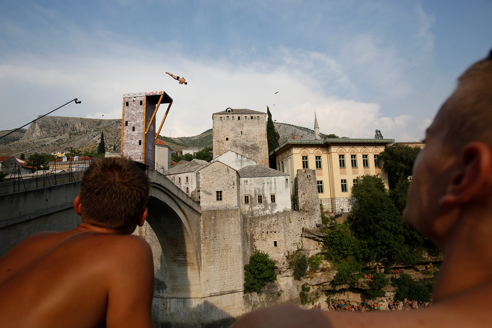Spectators watch as a diver jumps from the Old Mostar Bridge during the sixth stop of the Red Bull Cliff Diving World Series 2015, in Mostar, 140 kms south of Bosnian capital of Sarajevo, Saturday, Aug. 15, 2015. Fourteen of the world's best competitors took part in the competition diving from a 27 meter high bridge over the river of Neretva. (AP Photo/Amel Emric)
