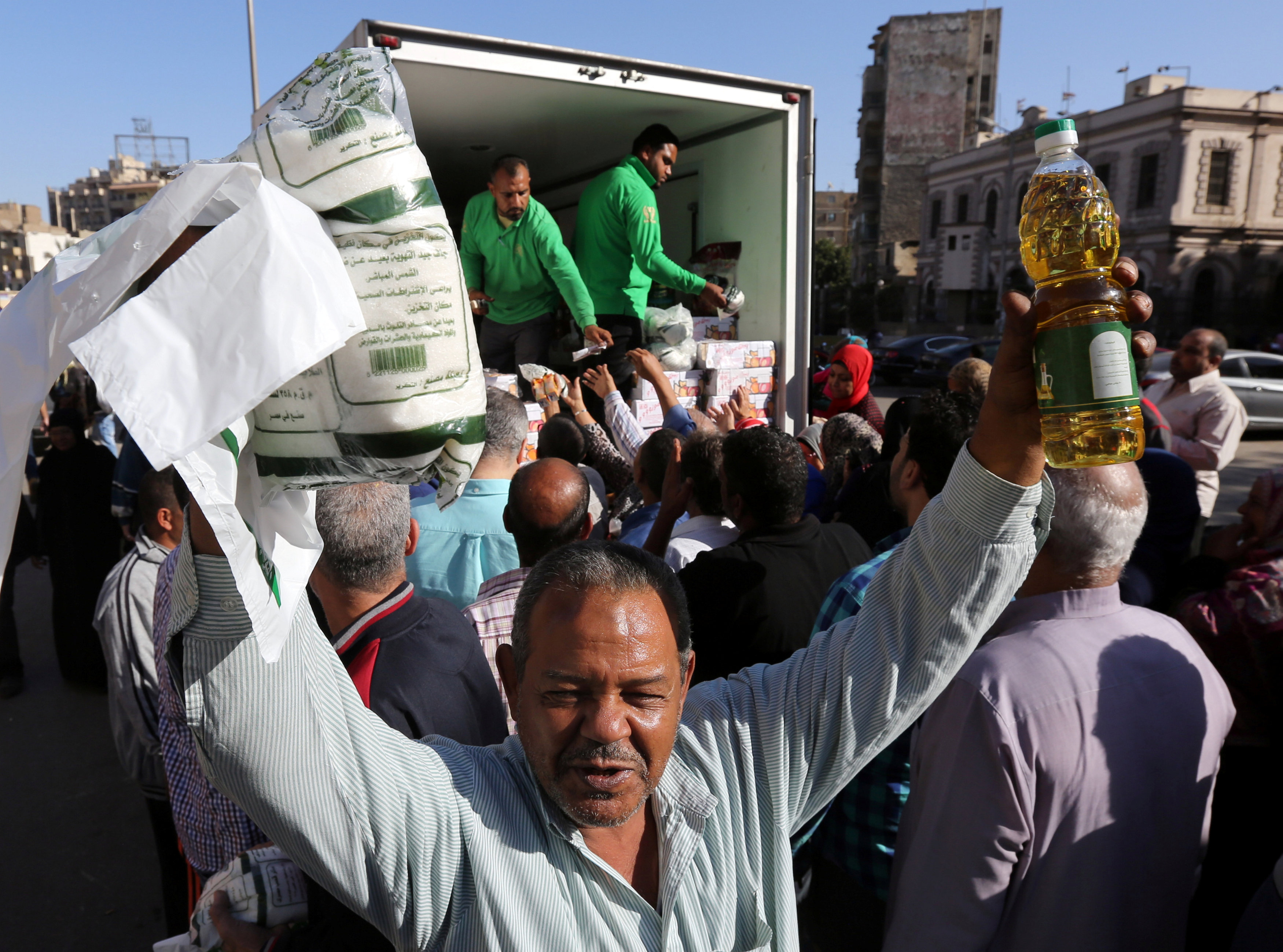 A man smiles as he carries subsidized sugar and oil after buying them from a government truck, after goods shortage in retail stores across the country and after the central bank floated the pound currency, in downtown Cairo, Egypt, November 7, 2016. REUTERS/Mohamed Abd El Ghany
