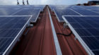 Sun Electric's Chief Executive Officer Matthew Peloso (R) walks along rows of rooftop solar panels, operated under the compan