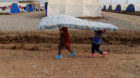 Displaced Iraqi children, who fled the Islamic State stronghold of Mosul, carry a mattress at Khazer camp, Iraq December 13, 