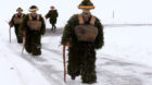 Men dressed as "Chlaeuse", figures that scare away evil spirits, carry round bells and cowbells as they walk on a partially s