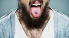 Young Happy Man Sticking Out Tongue Over a Grey Background