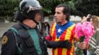 A man wearing a shirt with an Estelada (Catalan separatist flag) and holding carnations faces off with a Spanish Civil Guard 